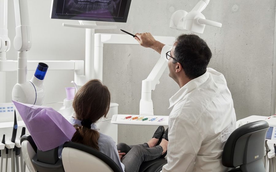 Dentista orientando a paciente mostrando um raio-X